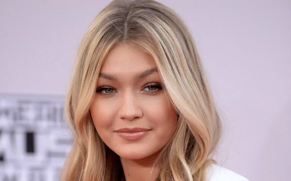 A HD desktop wallpaper featuring a portrait of an American model with green eyes and blonde hair, known as Gigi Hadid.