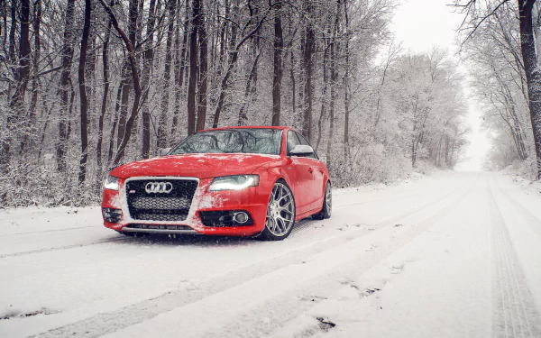 Red Audi S4 parked on a snowy winter road surrounded by snow-covered trees, captured in a high-definition desktop wallpaper showcasing snowfall and the crispness of winter.