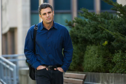 HD desktop wallpaper featuring Mark Ruffalo as Michael Rezendes from the movie Spotlight (2015) walking outdoors near greenery in a dark blue shirt.