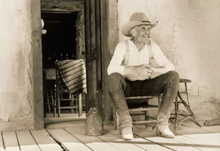 Sepia-toned HD desktop wallpaper featuring Robert Duvall as Gus from the movie Lonesome Dove, sitting on a porch in rustic Western attire.