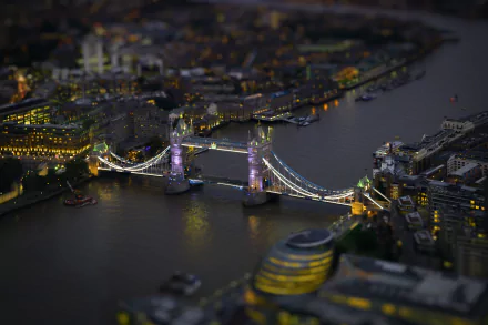 A tilt-shift photograph of Tower Bridge in London at night, illuminated against the dark river, showcasing the vibrant cityscape of the United Kingdom.