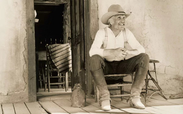 Sepia-toned HD desktop wallpaper featuring Robert Duvall as Gus from the movie Lonesome Dove, sitting on a porch in rustic Western attire.