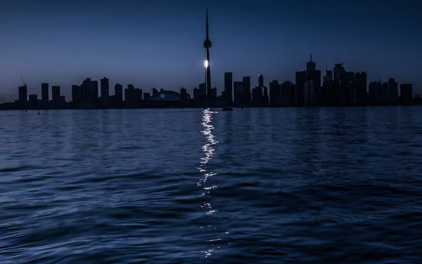 Nighttime view of Toronto’s skyscrapers reflecting on calm water, showcasing the city’s iconic skyline and man-made architecture in Canada.