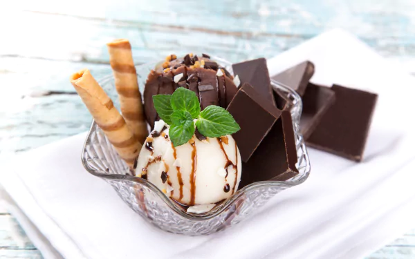 A 4K Ultra HD wallpaper featuring mint chocolate ice cream with chocolate wafers and chunks of chocolate on a rustic wooden table.
