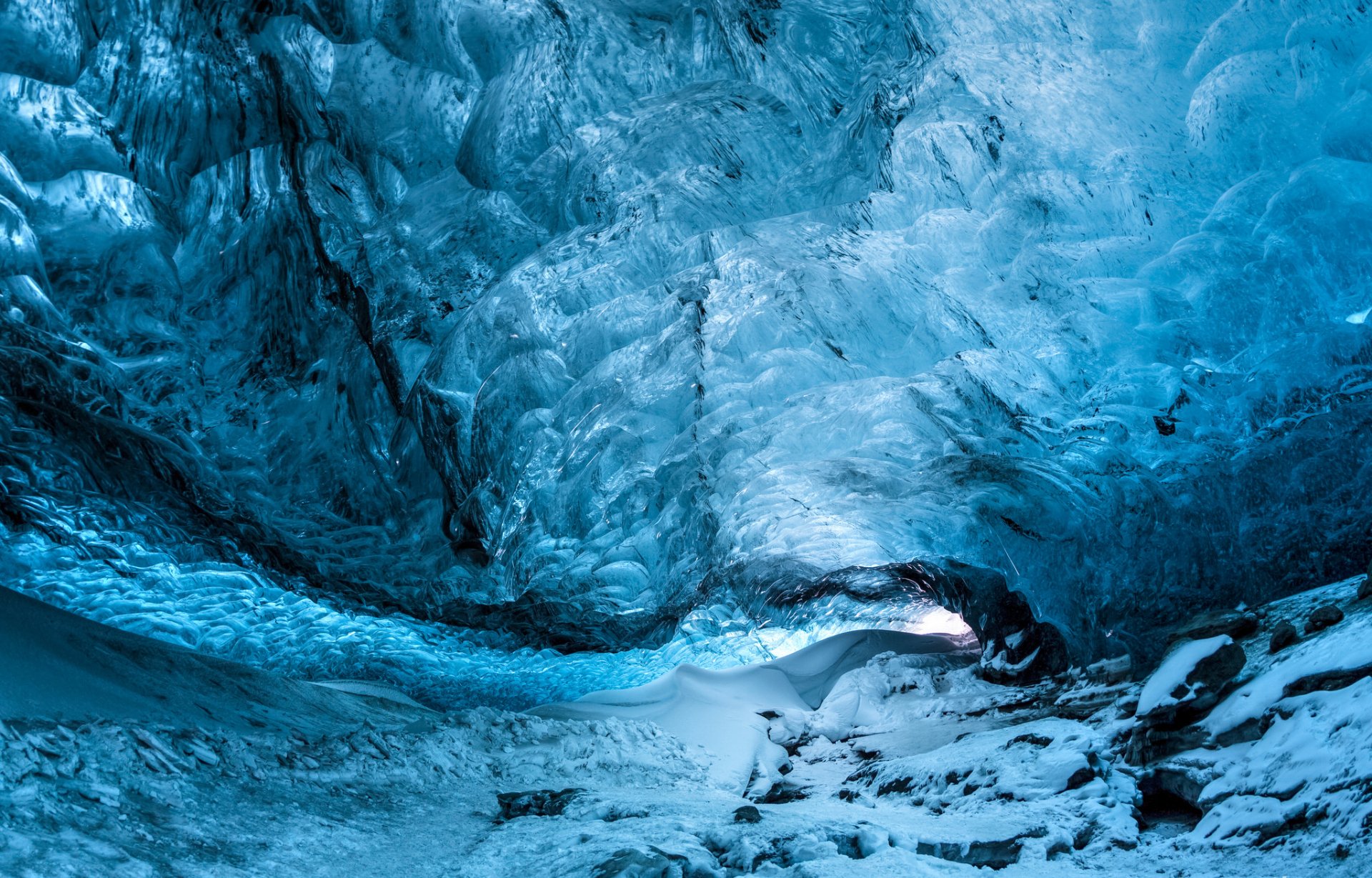 A captivating HD wallpaper showcasing a stunning ice cave with vibrant blue hues, highlighting the beauty of nature's frozen water formations.