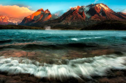 HD desktop wallpaper showcasing a vibrant Chilean mountain range with waves crashing onto a lake under a colorful sky.