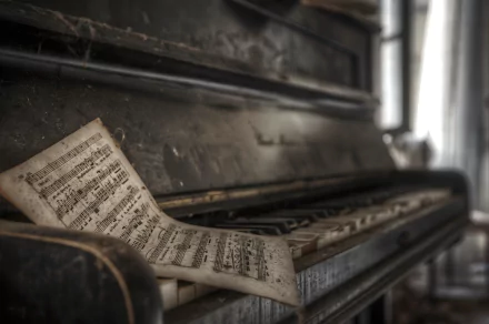 An abandoned piano with worn keys, accompanied by a sheet of music resting atop, creates a nostalgic atmosphere in this high-definition desktop wallpaper.