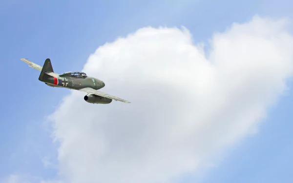HD desktop wallpaper featuring a Messerschmitt Me 262 military jet fighter warplane soaring against a bright blue sky with scattered clouds.