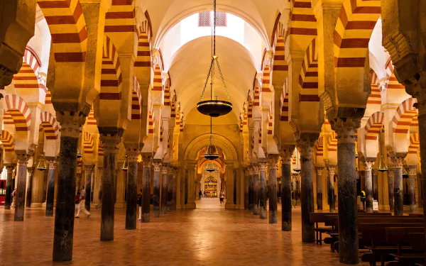 A stunning view of the interior of the Mosque-Cathedral in Córdoba, Spain, showcasing its iconic arches and striped columns in a warm, inviting atmosphere.