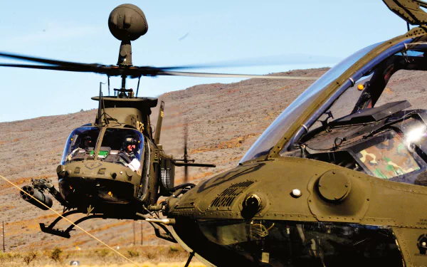 HD desktop wallpaper featuring two military Bell OH-58 Kiowa helicopters flying over a desert landscape under a clear blue sky.
