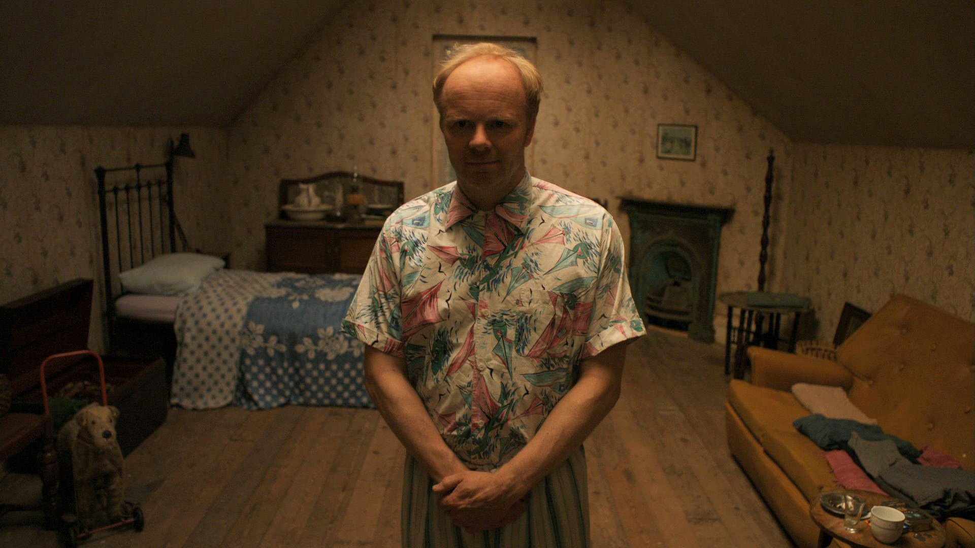 William Herrick from the TV show Being Human stands in a dimly lit attic bedroom with vintage decor, captured in an HD PC desktop wallpaper and background.
