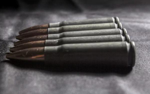 Close-up of man-made rifle bullets lined on a dark surface, HD PC desktop wallpaper/background.