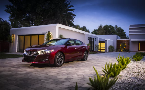 A red Nissan Maxima parked in front of a modern home at dusk, captured in an HD PC desktop wallpaper showcasing the vehicle and stylish architecture.