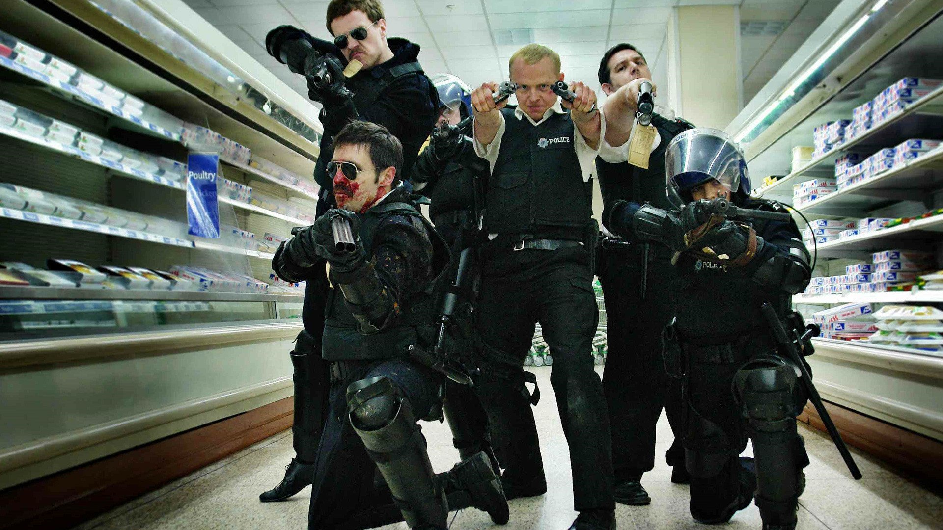 HD PC desktop wallpaper from the movie Hot Fuzz: a tactical police squad in black riot gear and sunglasses aims firearms down a supermarket aisle.