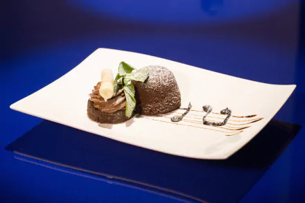 A simple chocolate cake and sweets served on a white plate against a blue background, captured in 4K Ultra HD for a PC desktop wallpaper.