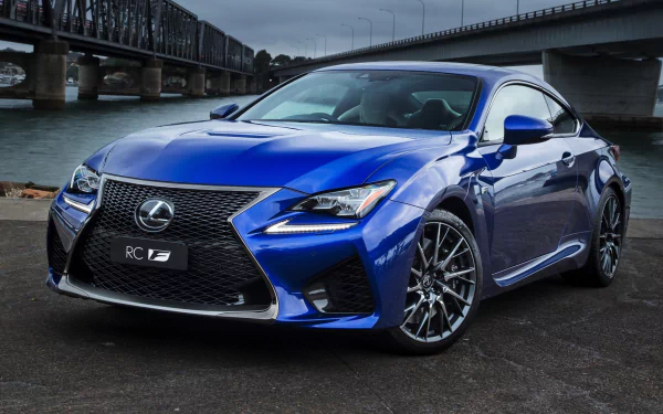 HD desktop wallpaper featuring a sleek blue Lexus RC sports car parked near an urban waterfront with bridges in the background.