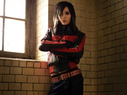 A high-definition desktop wallpaper featuring a member of Tokio Hotel, showcasing a striking look in a red and black leather jacket, set against a textured, industrial backdrop.