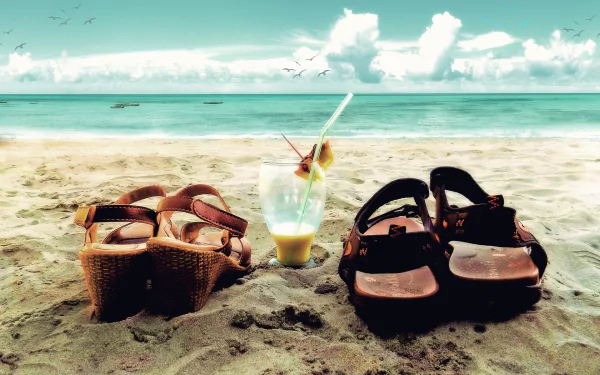 Two pairs of sandals next to a refreshing glass drink on the beach, with a serene horizon and romantic clouds in the background. A tranquil holiday vibe captured in this HD wallpaper.