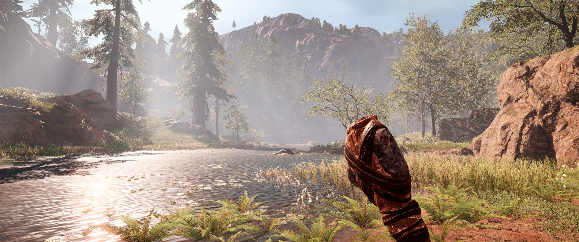Far Cry Primal video game 2K Quad HD PC desktop wallpaper background: misty prehistoric river valley with conifers, rocky cliffs and a wrapped wooden club in the foreground.