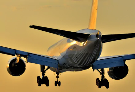 A Boeing 777 passenger plane silhouetted against a golden sunset, showcasing its sleek design and powerful engines. A stunning HD wallpaper for aviation enthusiasts.