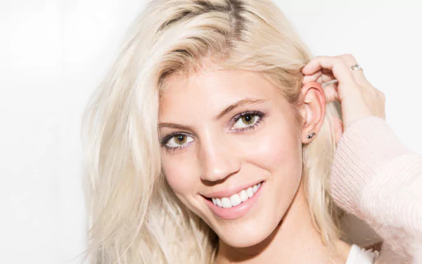 Close-up of a smiling blonde American model with green eyes and radiant skin, HD desktop wallpaper-style portrait.