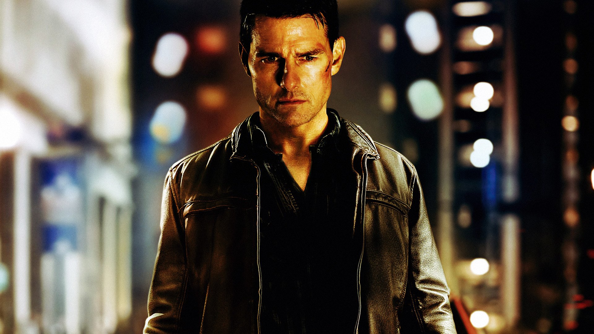 HD desktop wallpaper of Tom Cruise as Jack Reacher, featuring a moody, urban night scene with dramatic lighting and a focused expression.