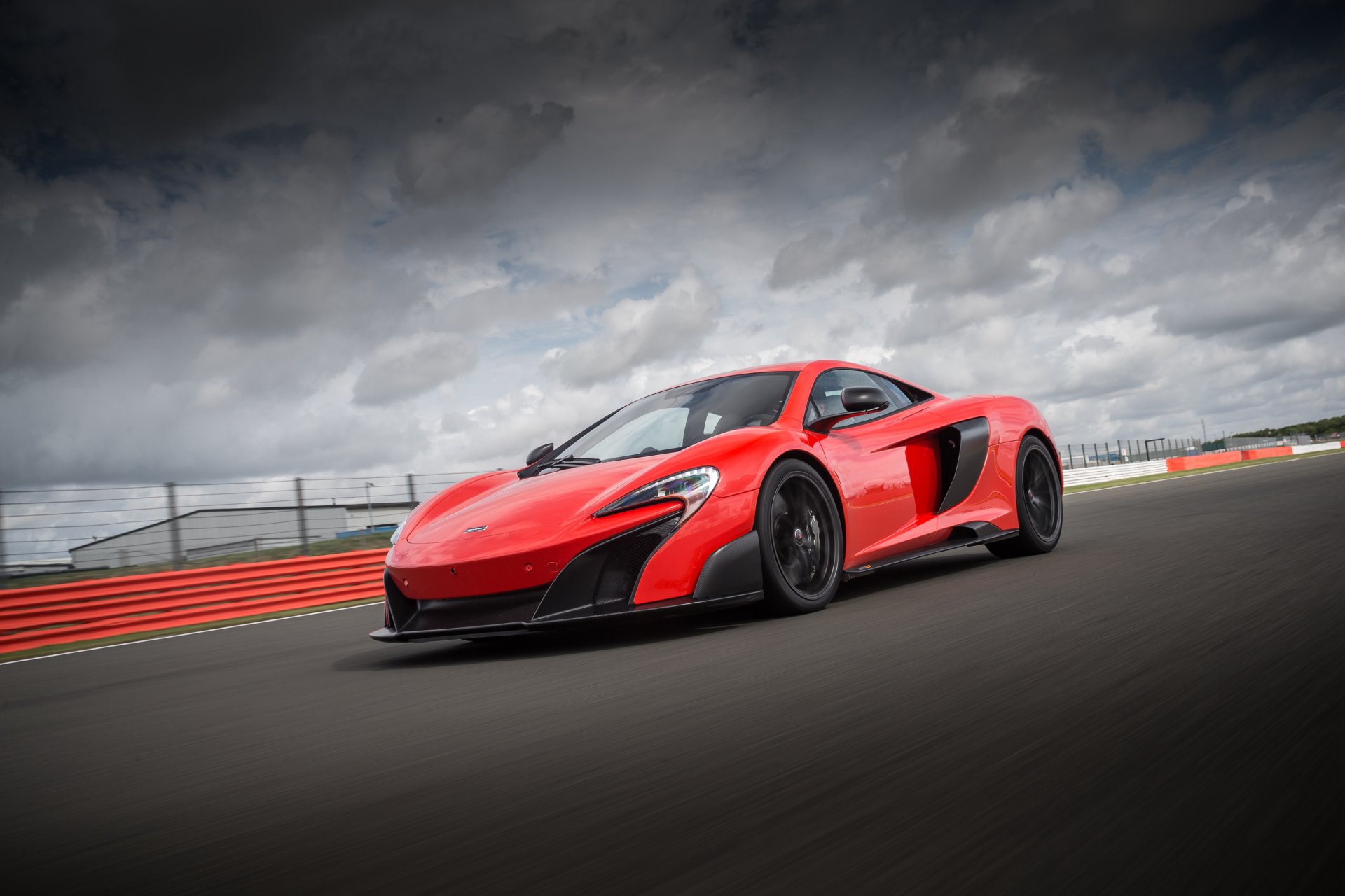Red McLaren 675LT supercar on a racetrack under dramatic clouds — 4K Ultra HD PC desktop wallpaper/background of a McLaren car and high-performance vehicle.