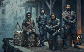 HD PC desktop wallpaper featuring the cast of the TV show The Musketeers in period costumes, set against a rustic, dimly lit backdrop.