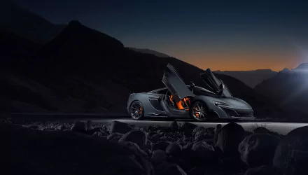 Silver McLaren 675LT supercar with butterfly doors open, set against a twilight mountainous landscape, featured as a HD PC desktop wallpaper and background.