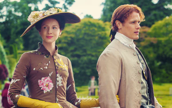 Claire Fraser and Jamie Fraser, portrayed by Caitriona Balfe and Sam Heughan, stand together outdoors in this vibrant HD wallpaper from the TV show Outlander.