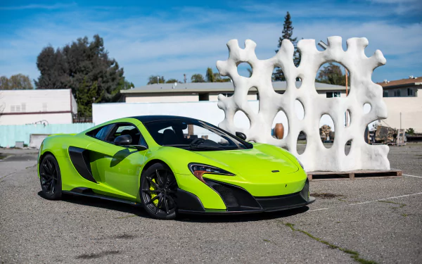 Bright green McLaren 675LT supercar parked outdoors with modern white sculpture and blue sky, captured as an HD PC desktop wallpaper and background.