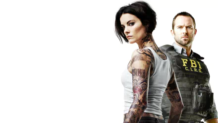 HD desktop wallpaper featuring Jaimie Alexander with extensive tattoos and Sullivan Stapleton from the TV show Blindspot, both in intense, focused poses.