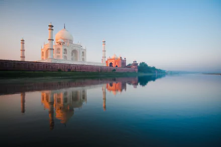 HD wallpaper of the Taj Mahal in Agra, India, showcasing its iconic dome and minarets reflected in the water, with a clear blue sky in the background.