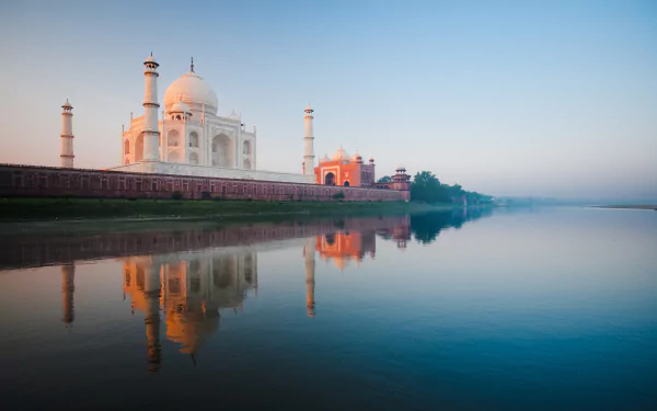 HD wallpaper of the Taj Mahal in Agra, India, showcasing its iconic dome and minarets reflected in the water, with a clear blue sky in the background.
