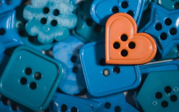HD PC desktop wallpaper background showing a close-up of man-made buttons — mostly blue square and flower shapes with one orange heart-shaped button.