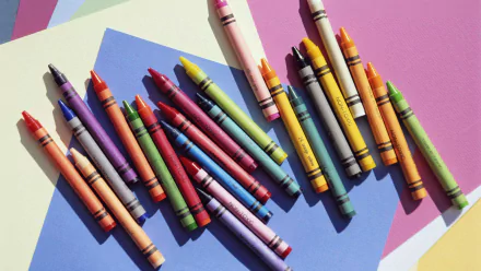 A vibrant array of crayons spread across a multicolored background, serving as an HD wallpaper showcasing creativity and color variety.