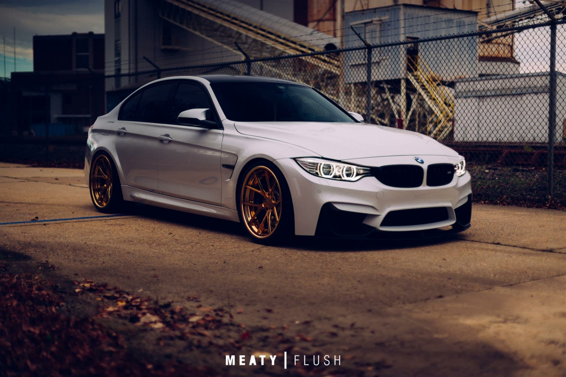 White BMW M3 vehicle parked on an industrial street with gold wheels and lowered stance — HD PC desktop wallpaper/background.