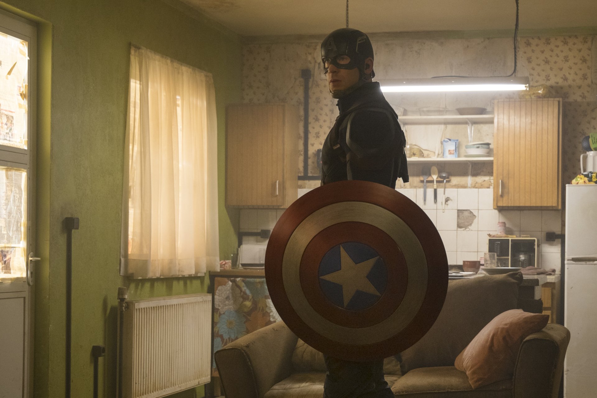 Captain America stands confidently in a kitchen setting, holding his iconic shield, from the movie *Captain America: Civil War*. This HD wallpaper captures a powerful moment.
