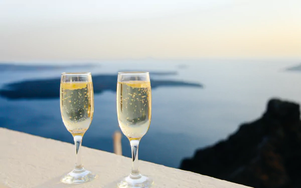 Two glasses of champagne sit on a ledge overlooking a serene coastal view, captured in 4K Ultra HD as a PC desktop wallpaper featuring drink and food themes.