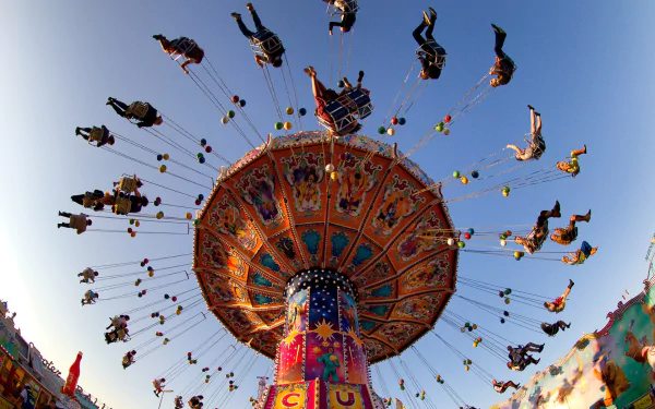 Vibrant carnival swing ride with people soaring through the colorful amusement park sky, captured in a dynamic HD desktop wallpaper.