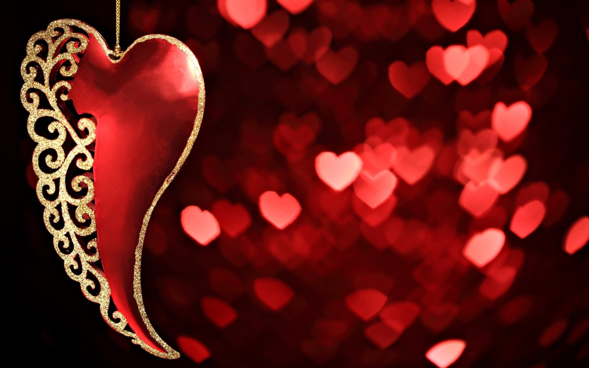 A striking red heart with intricate golden detailing against a blurred background of soft, illuminated hearts, embodying themes of love and artistry in a vibrant HD wallpaper.