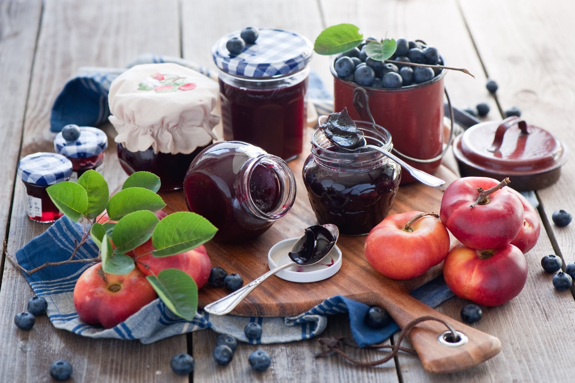 Still life of jars filled with blueberry jam, fresh blueberries, and apples arranged on a wooden surface, captured in vibrant 4K Ultra HD detail for a PC desktop background.