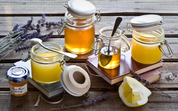 HD desktop wallpaper featuring a still life of jars filled with honey and lemon wedges on a rustic wooden surface, accented by sprigs of lavender.
