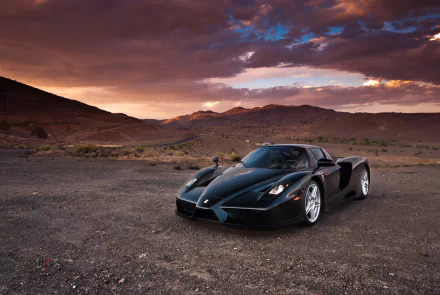 Black Ferrari Enzo supercar parked on a desert plain at sunset — 2K Quad HD PC desktop wallpaper background