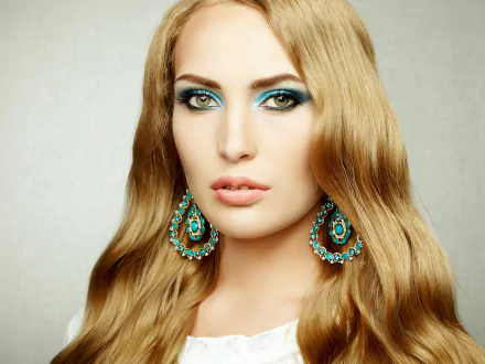 HD desktop wallpaper featuring a blonde woman with striking green eyes, wearing ornate blue and gold earrings.
