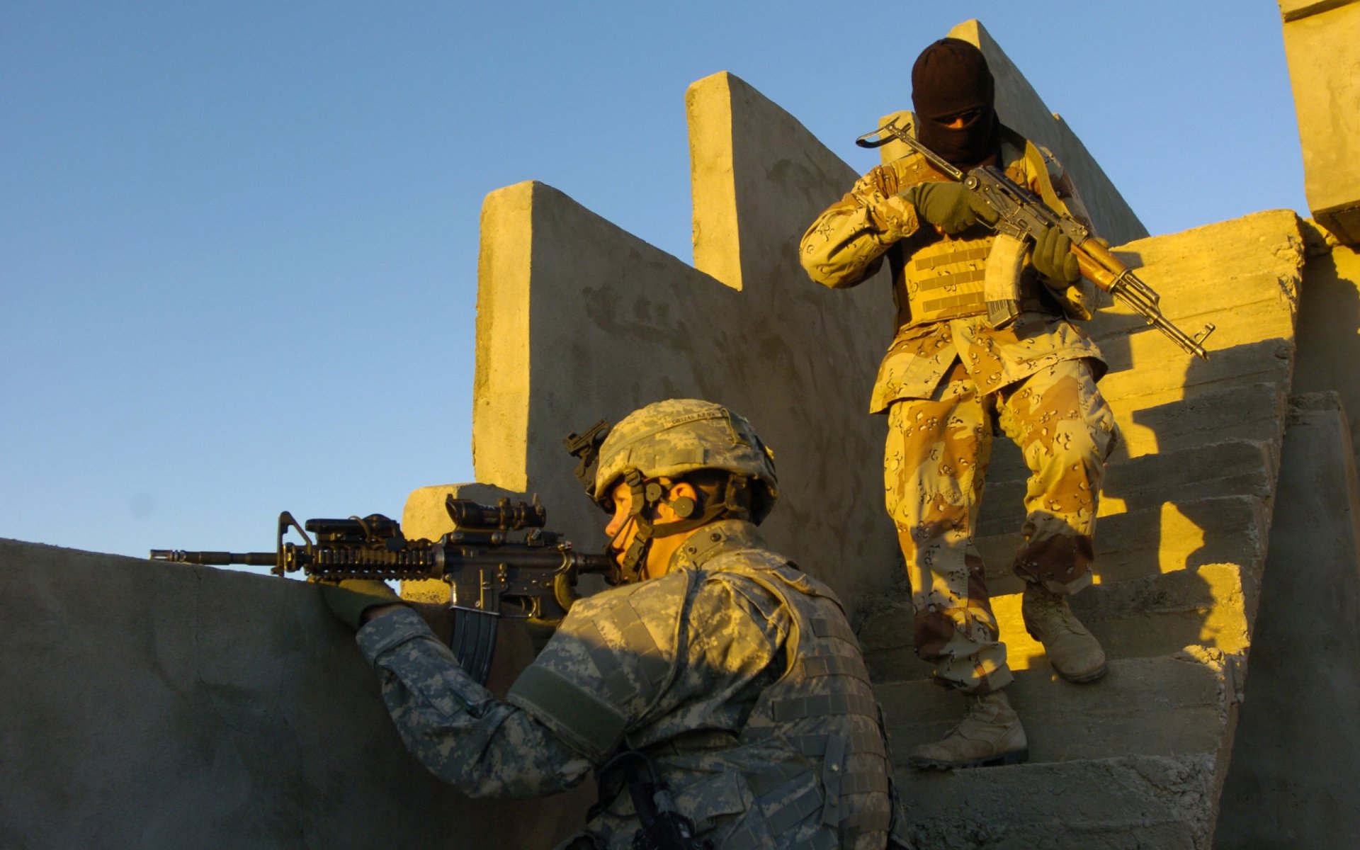A soldier in military gear aims a rifle while another in tactical clothing moves cautiously down stairs, illuminated by golden sunlight, creating a striking HD desktop wallpaper.