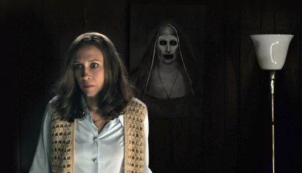 A haunting scene from The Conjuring 2 featuring Vera Farmiga, showcasing her tense expression with an eerie figure in the background. HD wallpaper capturing the film's chilling atmosphere.