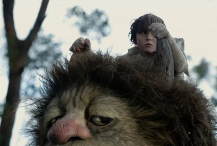 HD PC desktop wallpaper from the movie Where the Wild Things Are featuring a boy riding on the back of a large, furry creature in a forest setting.