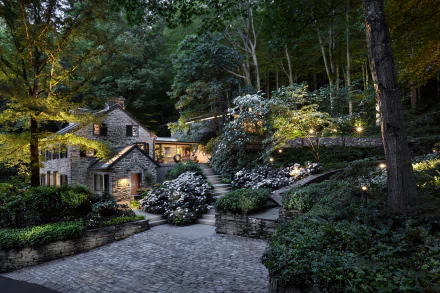 A charming house nestled among lush greenery in Yorkshire, England, features beautiful landscaping and warm lighting, creating a serene and inviting atmosphere.