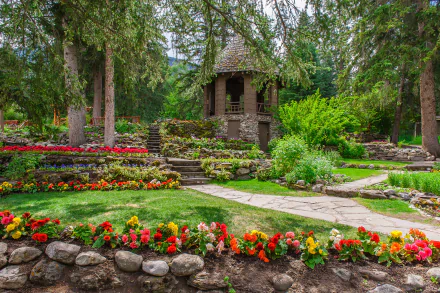4K Ultra HD PC desktop wallpaper: a manicured garden with colorful flower beds, stone paths and a man-made gazebo tucked among tall trees.